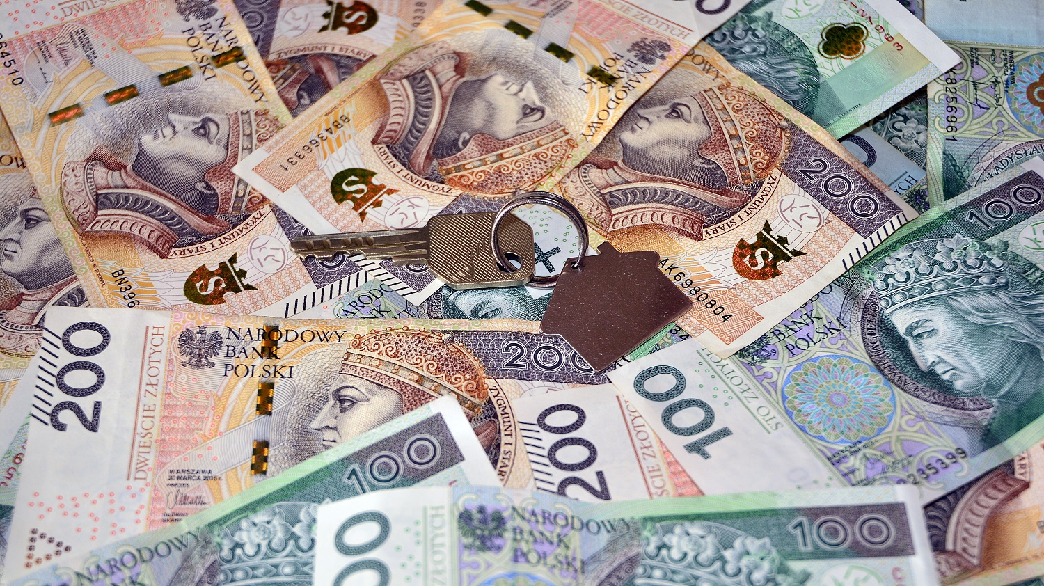 Polskie banknoty o dużych nominałach, a na nich klucz z brelokiem w kształcie domu